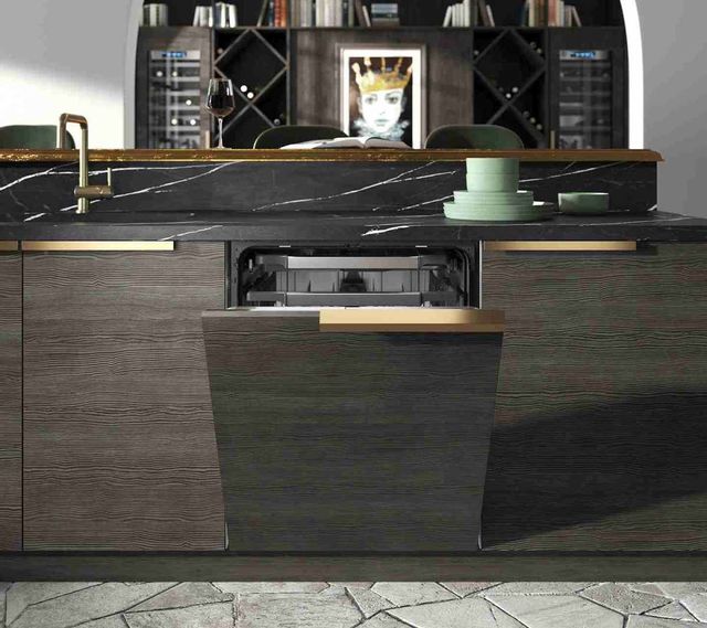 front view of a dark wood panel dishwasher in a modern luxury kitchen island with a sink, black marble countertops, and gold accents