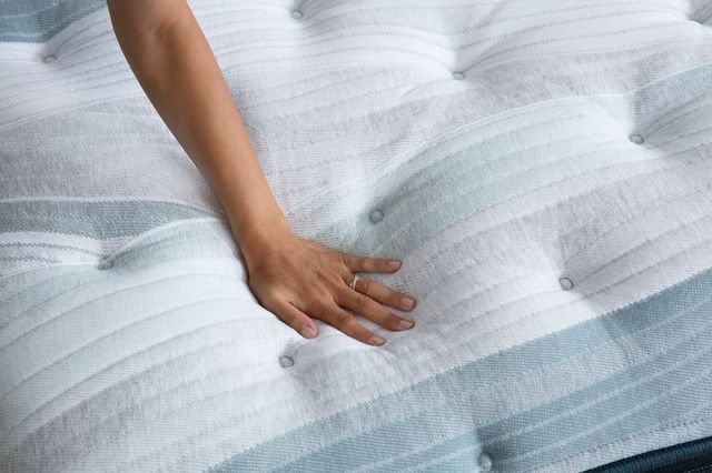 top view of an arm and hand pressing onto a pillow top mattress