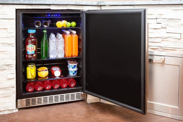 front view of an undercounter refrigerator in a stone countertop, open and full of beverages and small snacks