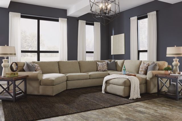front view of a modern living room with a beige big couch, dark gray walls, and matching accents throughout