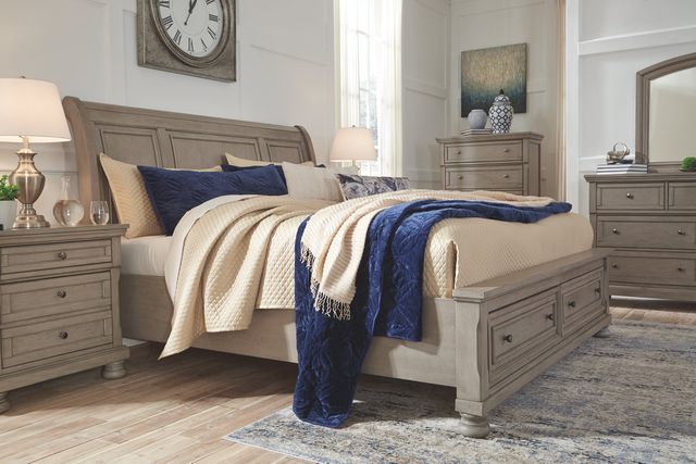 Side view of a modern traditional bedroom with a light wood sleigh bed with beige and blue blankets and pillows on top