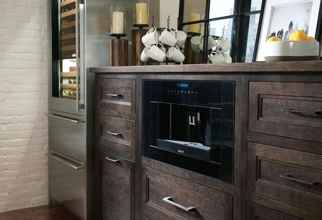 close view of a built in coffee maker in dark brown bottom cabinets in a kitchen coffee area