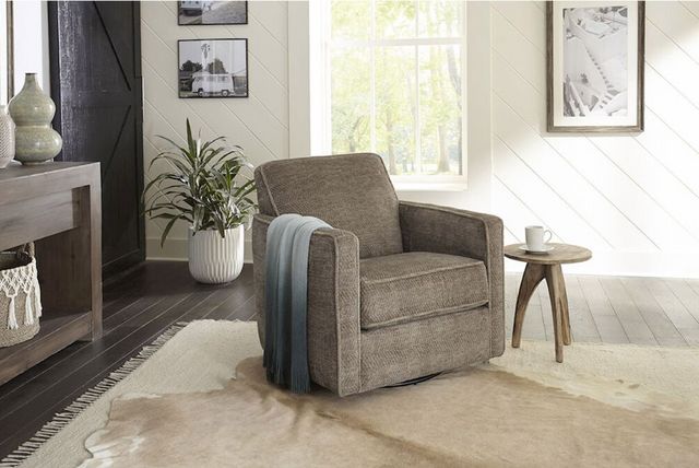 front view of a modern living room with a swivel chair centered and a plant in the back, dark wood covers the floors and white wall paneling