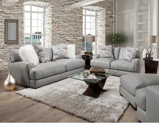 view of a formal living room with light gray furniture and a light white brick wall in the background