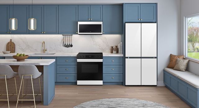 front view of a modern kitchen with black and white appliances, and a white french door refrigerator all in blue cabinetry