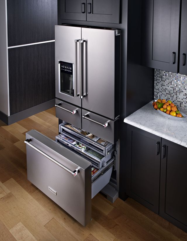 Stainless steel KitchenAid 5 door French door refrigerator in a kitchen with dark cabinets