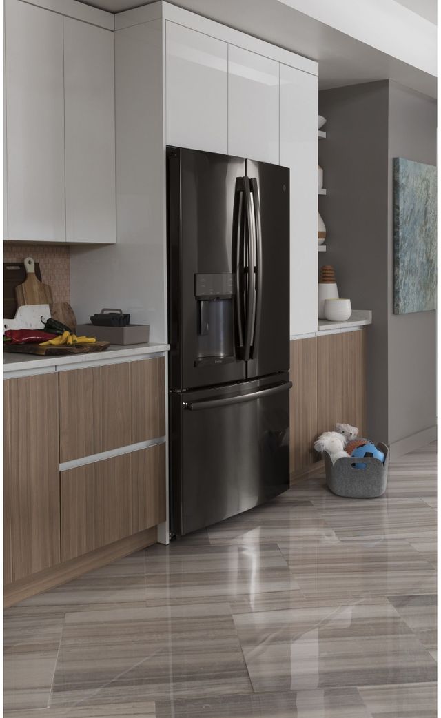 A black stainless steel French door refrigerator is installed in a kitchen with white and wood cabinets