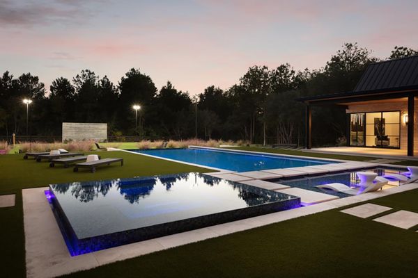 Outdoor lighting surrounds the pool and leisure are of a Texas home